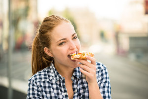 51640454 - teenager lifestyle - young woman eating pizza outdoor in street